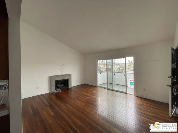 an empty room with wooden floor fireplace and windows