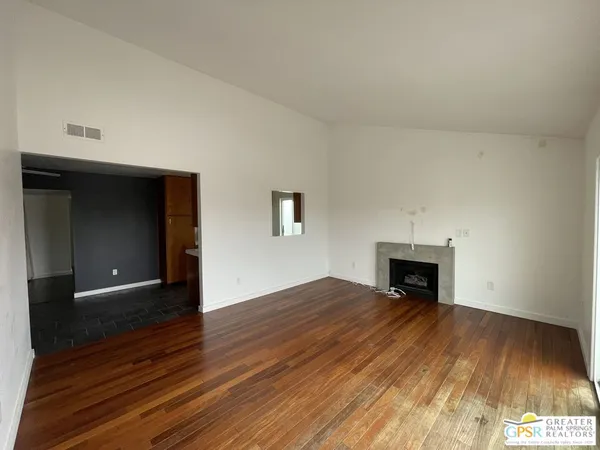 a view of empty room with wooden floor and fireplace
