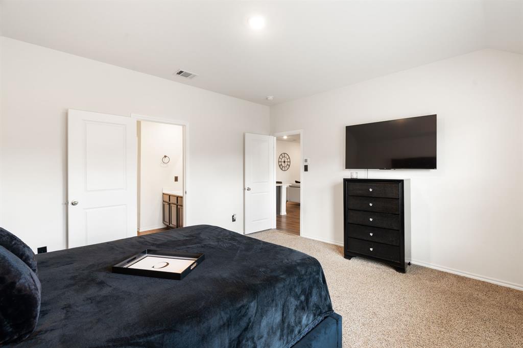 3413 Perman Drive Forney, TX 75126 - Photo 15 of 33 a bedroom with a bed and a flat tv screen on a dresser