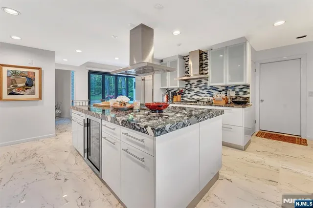 a kitchen with stainless steel appliances granite countertop a stove top oven a sink a dining table and chairs with wooden floor