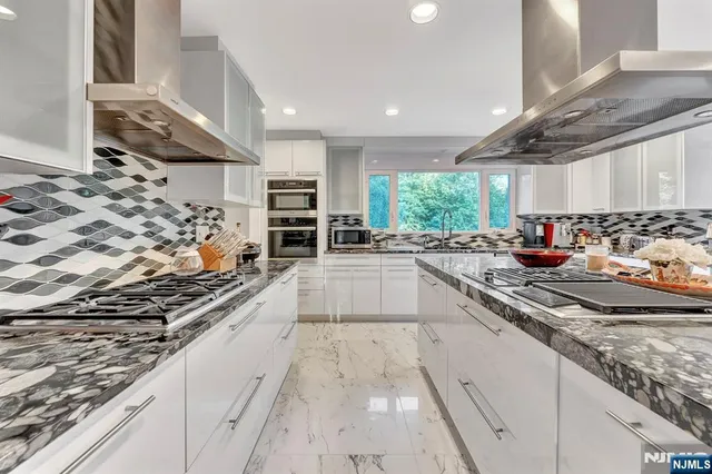 a large kitchen with stainless steel appliances granite countertop a lot of counter space and a sink