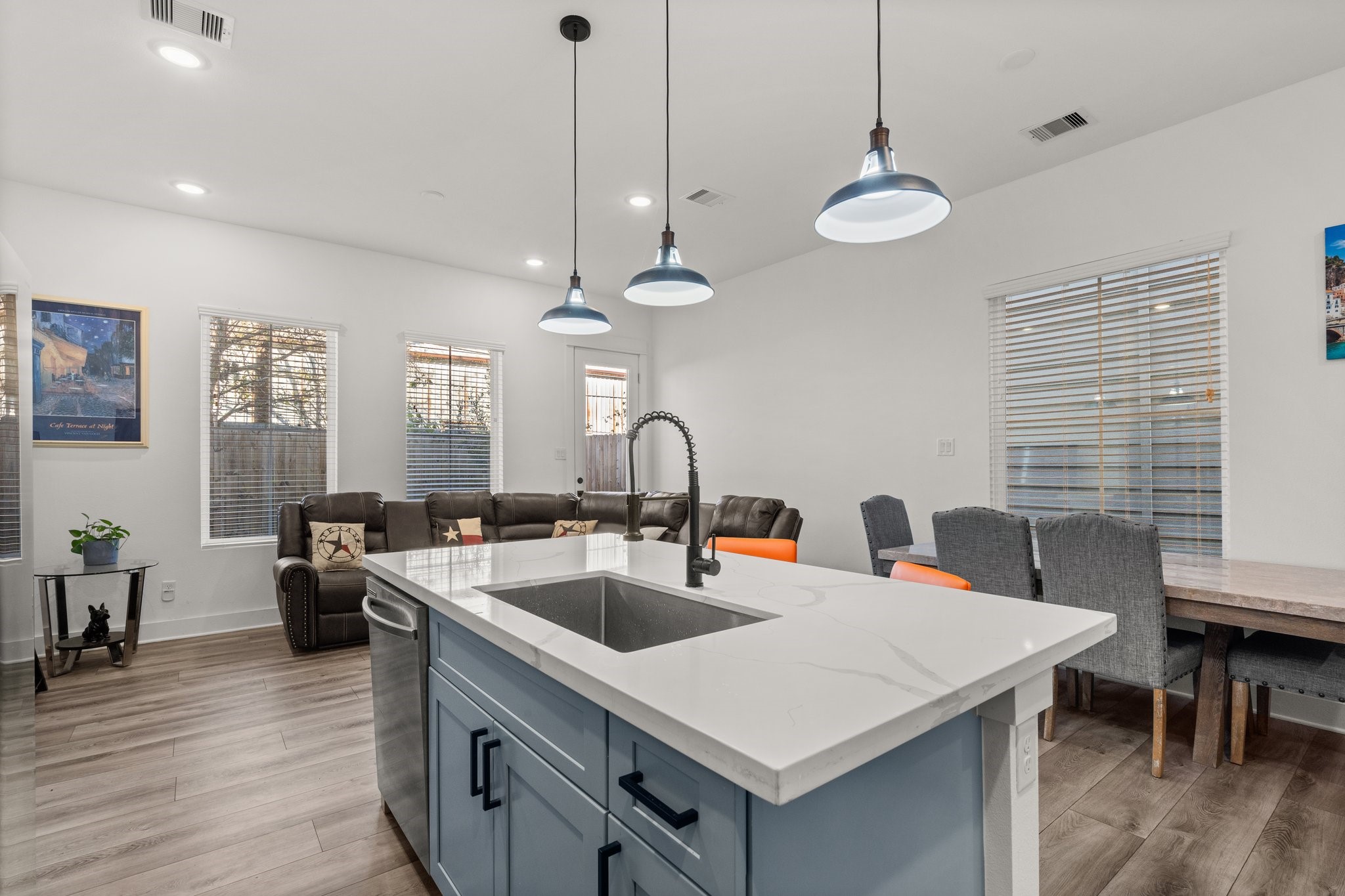 2928 Stevens Street Houston, TX 77026 - Photo 6 of 30 This inviting open-concept space features a modern kitchen with a large island, sleek pendant lighting, and a cozy living area. The room is bright with natural light from multiple windows, complemented by wood flooring and contemporary furnishings. Perfect for entertaining and family gatherings.