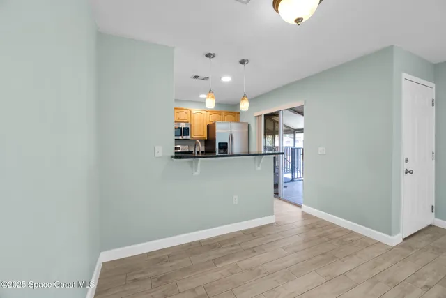 an empty room with wooden floor a ceiling fan and windows