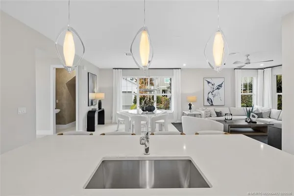 a kitchen with stainless steel appliances granite countertop a dining table chairs and a refrigerator