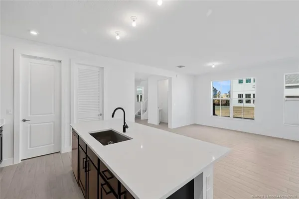 a large white kitchen with kitchen island a sink a center island stainless steel appliances and a refrigerator