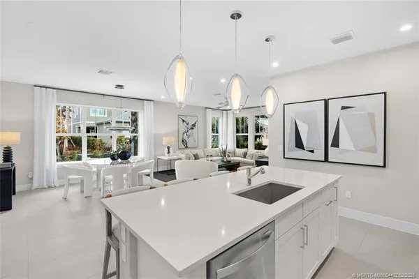 a large white kitchen with stainless steel appliances kitchen island granite countertop a refrigerator and a stove top oven