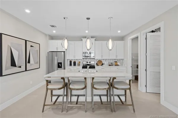 a kitchen with stainless steel appliances a refrigerator a stove a sink a dining table and chairs