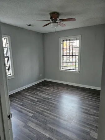 an empty room with wooden floor and windows