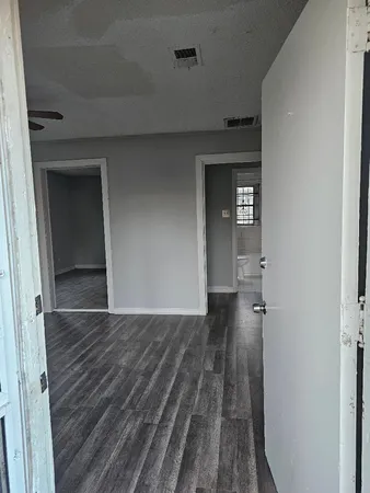 a view of a hallway with wooden floor and a bathroom