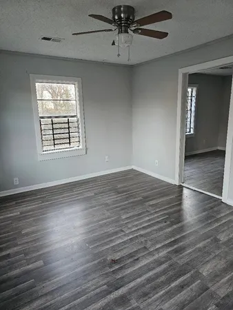 an empty room with wooden floor chandelier and windows