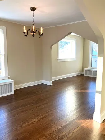 a view of a livingroom with wooden floor a ceiling fan and windows