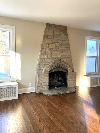 an empty room with wooden floor fireplace and windows