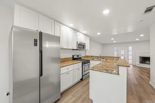 a kitchen with stainless steel appliances granite countertop a refrigerator a stove and a sink