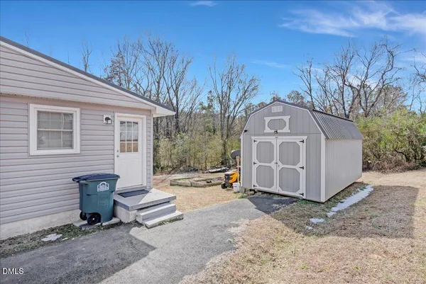 a view of backyard of house with outdoor seating and trees