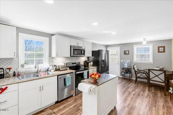 a kitchen with a sink a stove cabinets and wooden floor