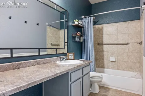 a bathroom with a granite countertop sink a toilet and shower