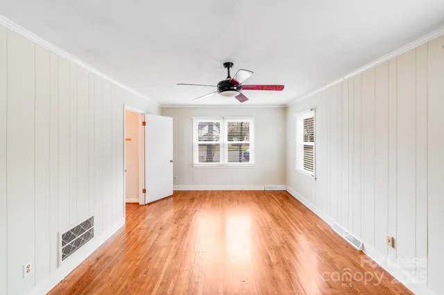 a view of an empty room with a window and wooden floor