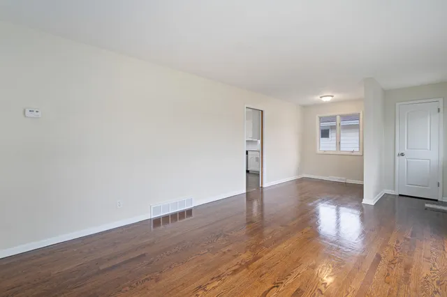 an empty room with wooden floor & windows