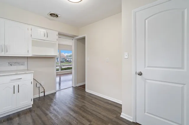 a kitchen with white cabinets and wooden floor