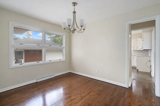 a view of empty room with wooden floor and window