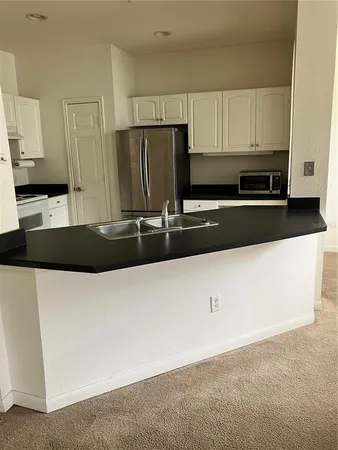 a kitchen with granite countertop a refrigerator a sink a stove a microwave and wooden cabinets