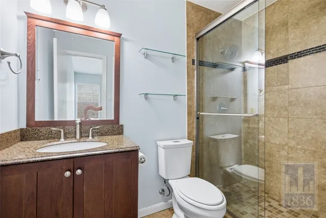 a bathroom with a granite countertop sink toilet a mirror and shower