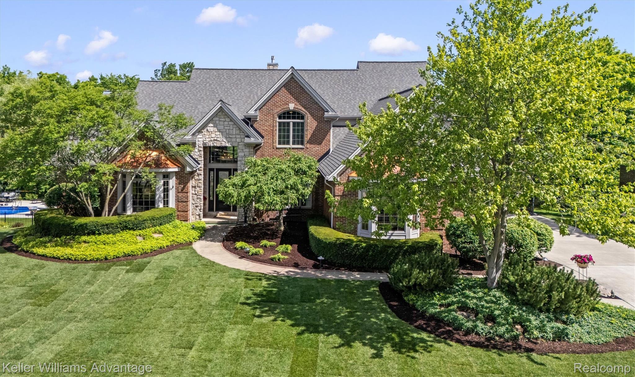 22878 Tree Top Court South Lyon, MI 48178 - Photo 62 of 75 Stately brick and stone exterior with a gray shingle roof, featuring multiple gables and dormer windows