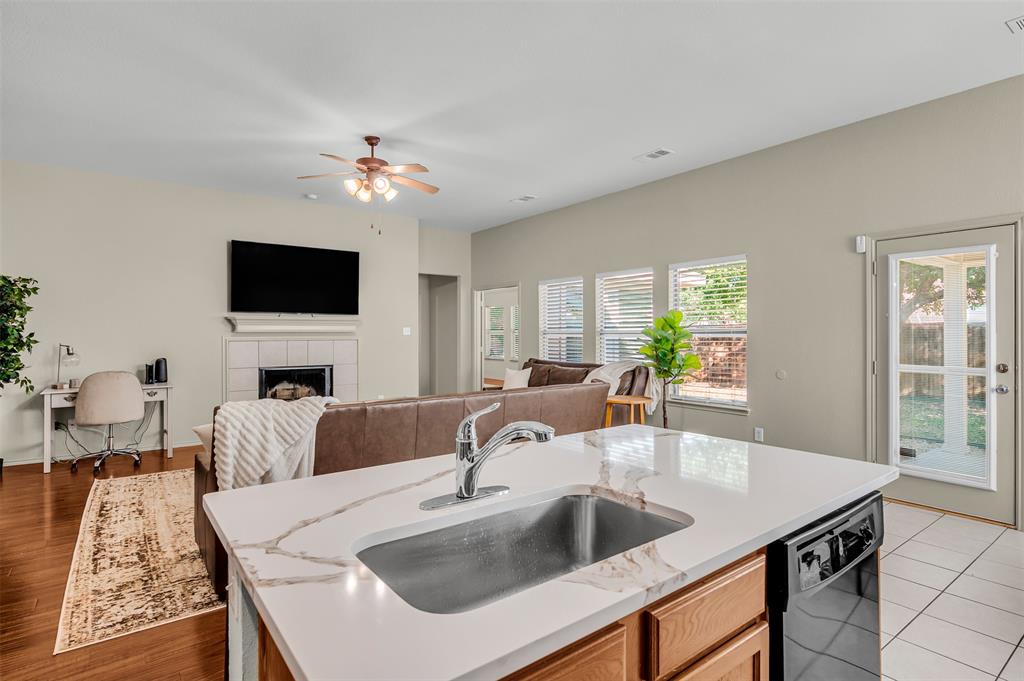12109 Ridge Tree Road Fort Worth, TX 76036 - Photo 29 of 29 Kitchen with a tiled fireplace, black dishwasher, open floor plan, light stone countertops, and a ceiling fan