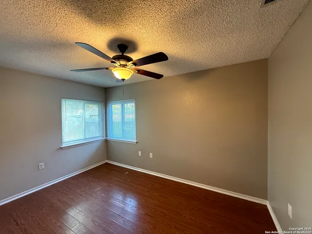 a view of an empty room with a window and wooden floor