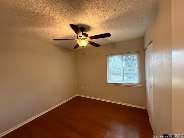 an empty room with a window and a fan