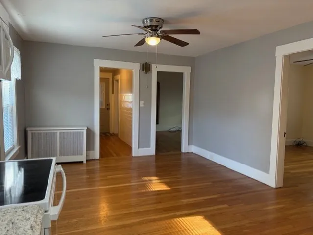 an empty room with wooden floor cabinet and windows