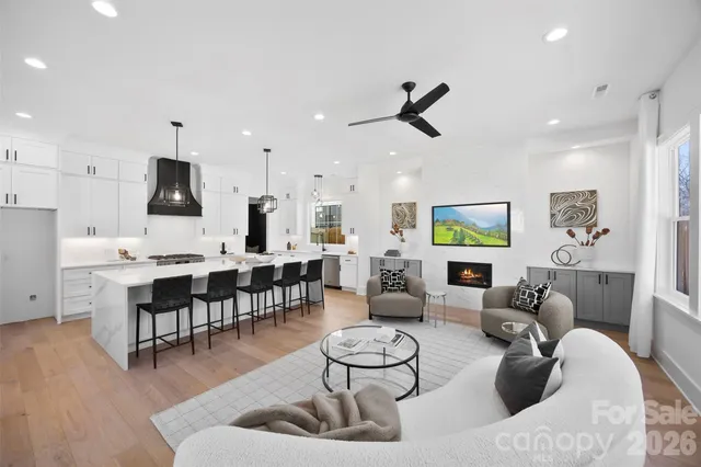a living room with furniture kitchen view and a wooden floor
