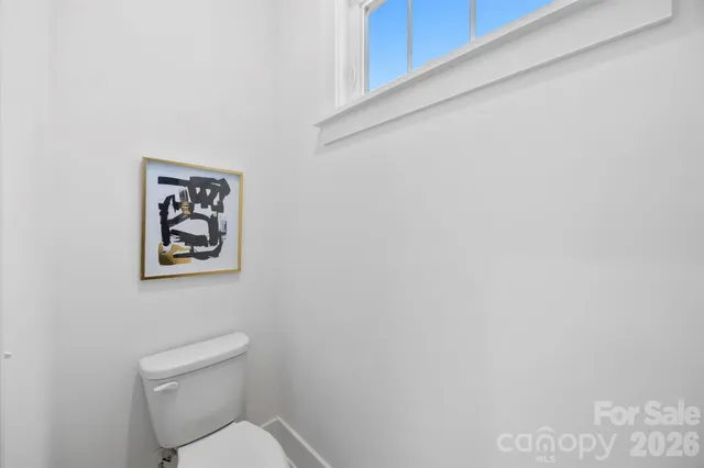 a white toilet sitting next to a white wall
