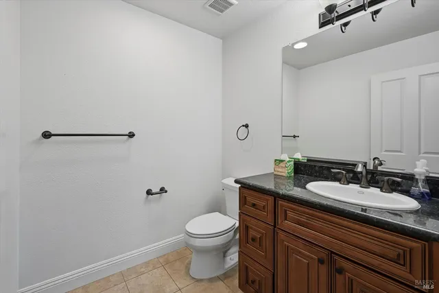 a bathroom with a granite countertop sink a toilet and a mirror