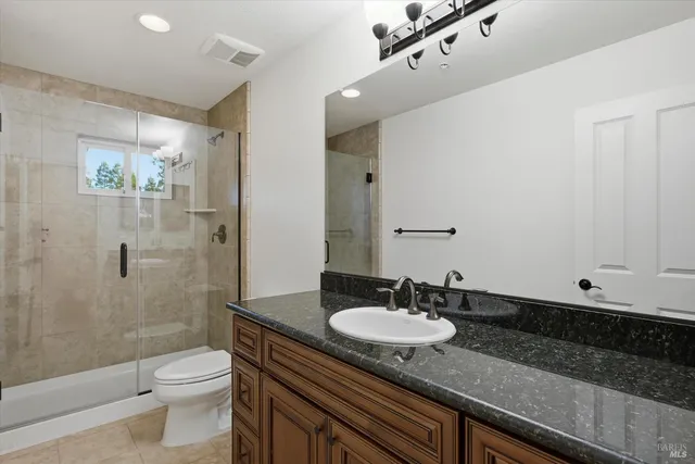 a bathroom with a granite countertop sink toilet a mirror and shower
