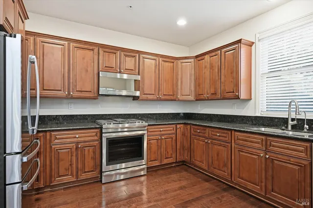 a kitchen with stainless steel appliances granite countertop wooden cabinets and a stove top oven
