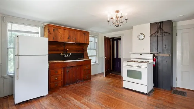 a kitchen with granite countertop a refrigerator a stove top oven and wooden floor