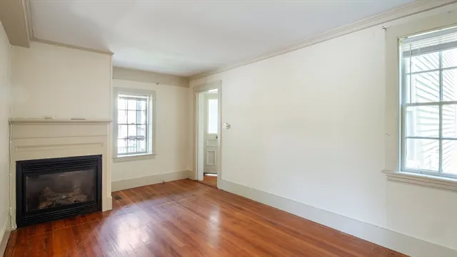 an empty room with wooden floor fireplace and windows
