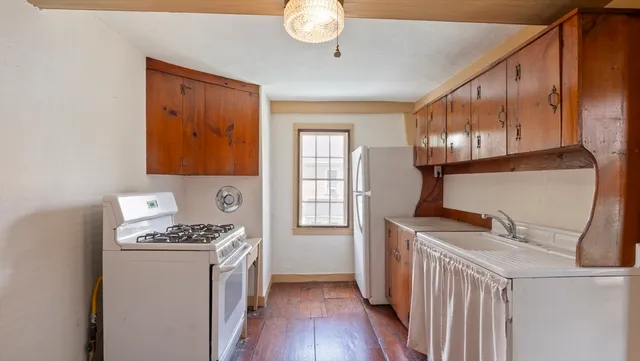 a kitchen that has a lot of cabinets stainless steel appliances and wooden floor