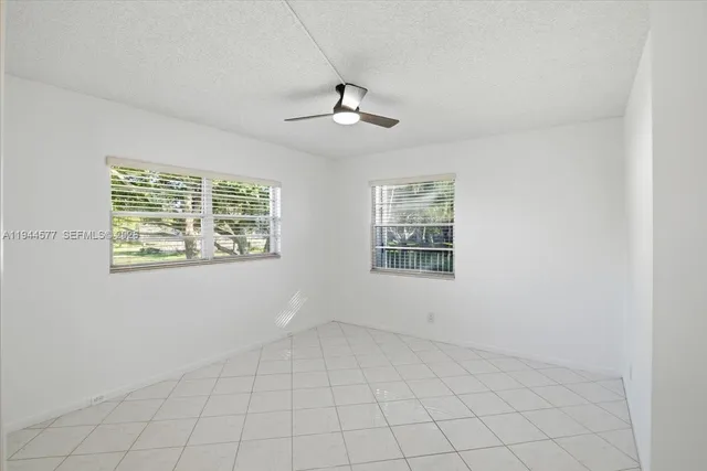 an empty room with windows and ceiling fan