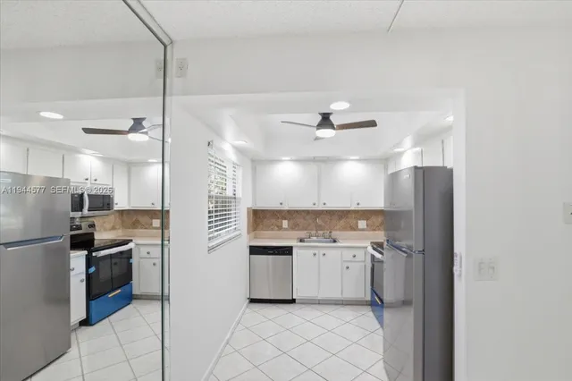 a kitchen with kitchen island white cabinets and stainless steel appliances