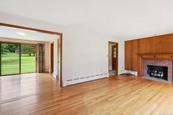 an empty room with wooden floor fireplace and windows