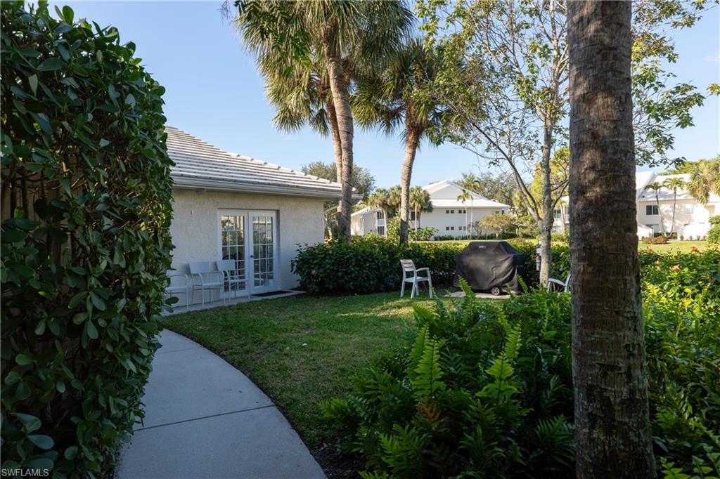 790 Willowbrook Drive, Unit 305 Naples, FL 34108 - Photo 20 of 23 a view of backyard with table and chairs and a large tree