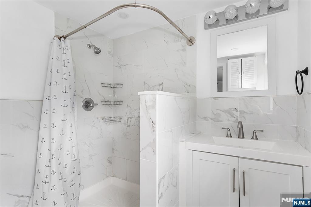 67 Nolans Point Road Lake Hopatcong, NJ 07849 - Photo 17 of 43 a bathroom with a sink a mirror a shower and vanity