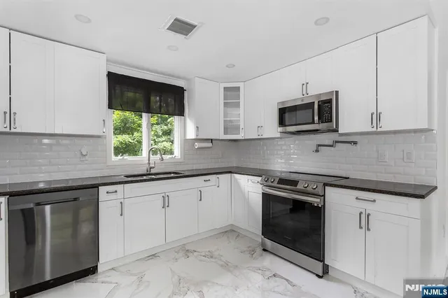 a kitchen with cabinets stainless steel appliances and sink