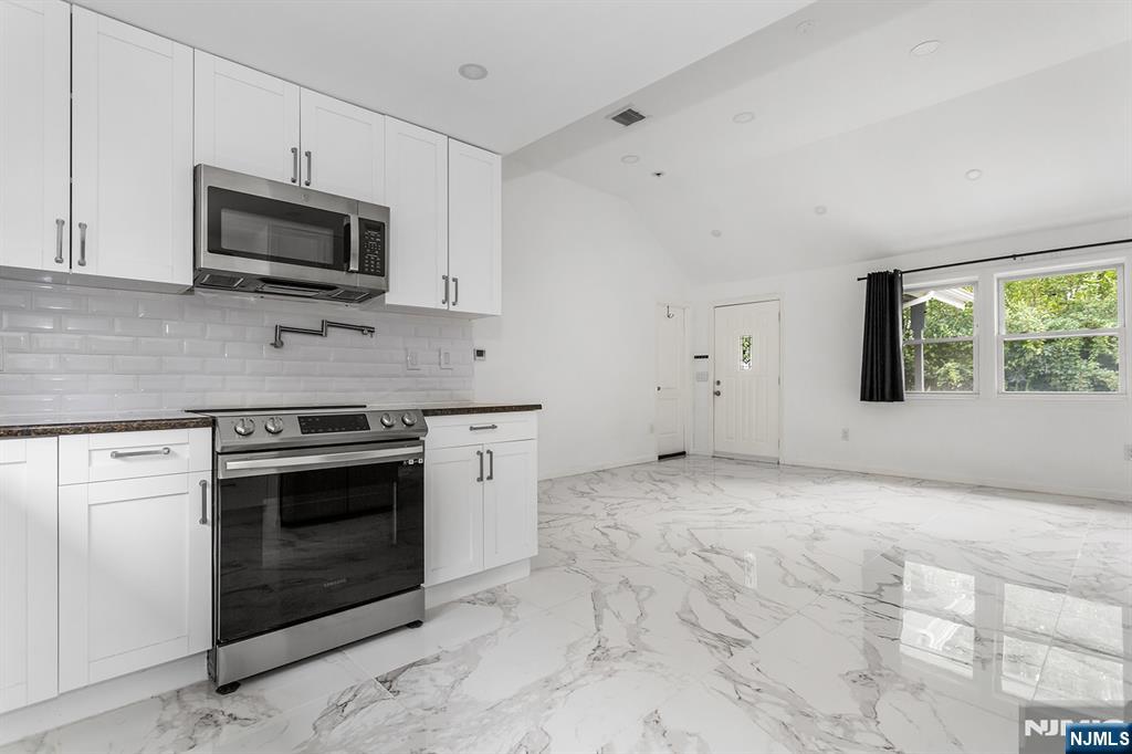 67 Nolans Point Road Lake Hopatcong, NJ 07849 - Photo 10 of 43 a kitchen with granite countertop a stove a microwave and white cabinets