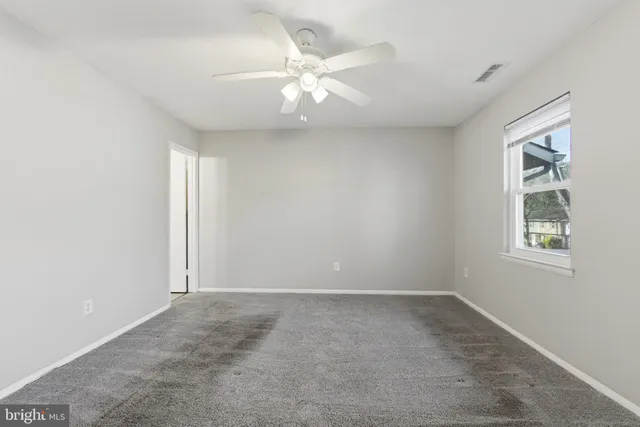 an empty room with windows and fan