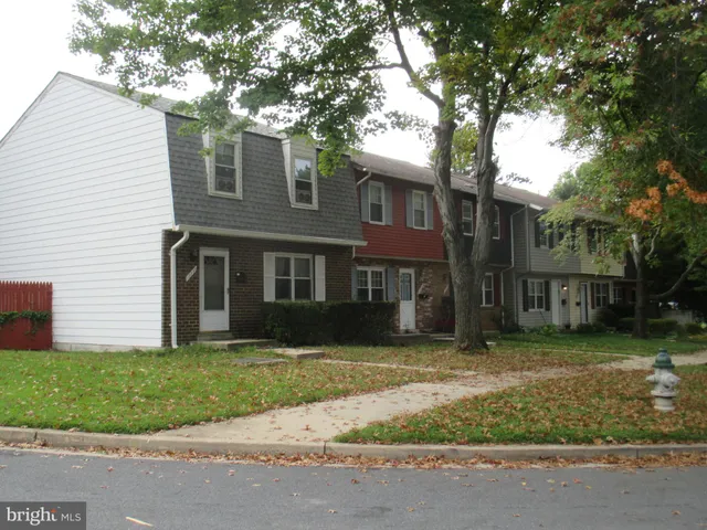 a view of a brick house next to a yard with big trees