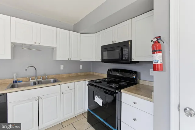 a kitchen with granite countertop white cabinets and black appliances