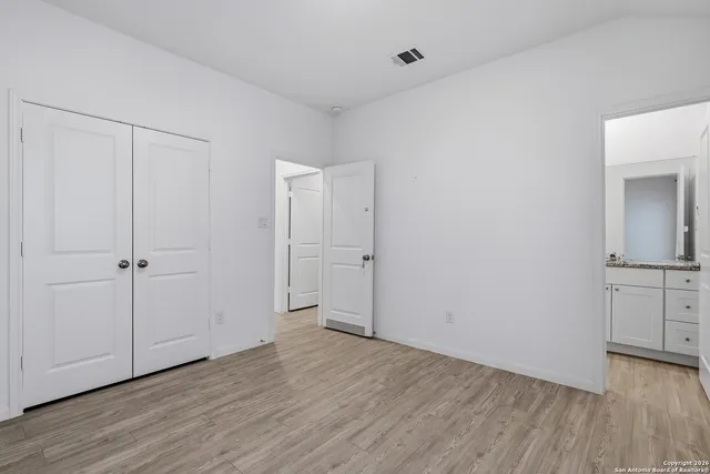 a view of an empty room with closet and wooden floor